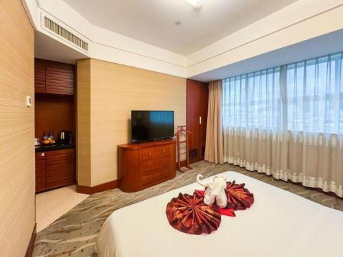 a hotel room with a bed and a flat screen tv at Xiamen Jingmin Central Hotel in Xiamen