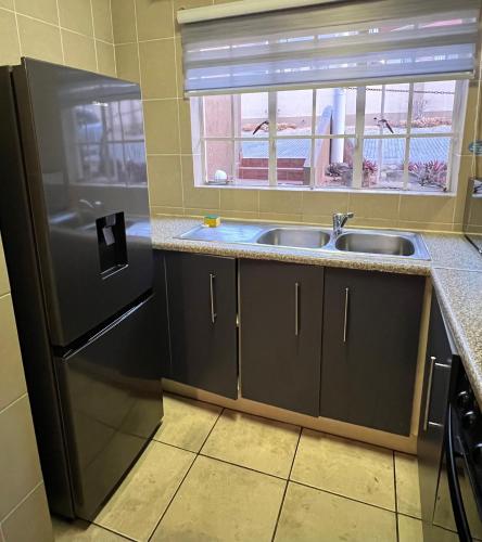 a kitchen with a sink and a refrigerator at Luxstay in Nelspruit
