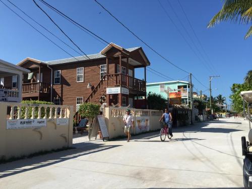 two people riding a bike down a street in front of a house at Blue Wave Guest House in Caye Caulker