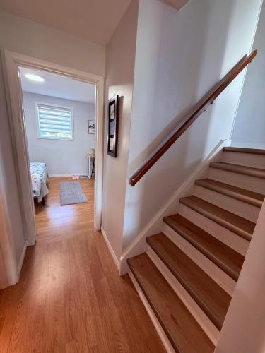 a staircase in a home with white walls and wooden floors at Your Cozy Home in Thunder Bay