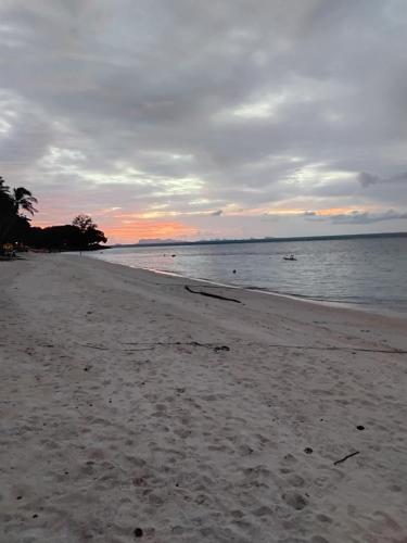 a beach with a cloudy sky and the ocean at Green Salad Hostel in Ban Bang Po