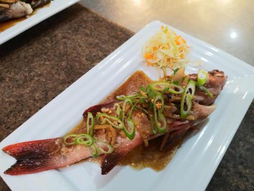a white plate with a piece of fish with green onions at Asia Grand View Hotel in Coron