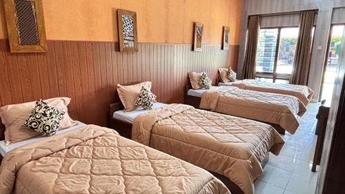 a room with three beds with pillows on them at Candra Dewi Yogyakarta in Timuran