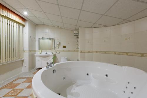a bathroom with a large white tub and a sink at Hotel Rial in Vladivostok