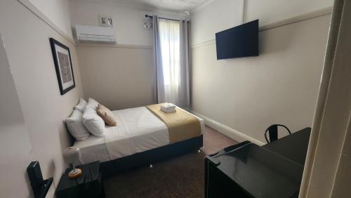 a small bedroom with a bed and a window at Islington Barracks Hotel in Hamilton