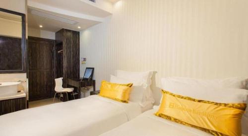 a bedroom with two white beds with yellow pillows at Harbour Bay Hotel in Hong Kong