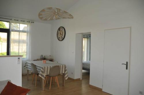 a dining room with a table and a clock on the wall at Charmante maison près de la gare 2 chambres in Jonzac