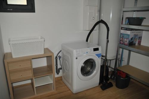 a washing machine with a vacuum next to a shelf at Charmante maison près de la gare 2 chambres in Jonzac