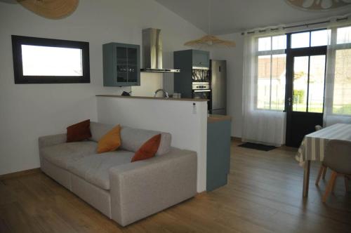 a living room with a couch and a kitchen at Charmante maison près de la gare 2 chambres in Jonzac