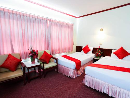 two beds in a hotel room with red accents at Chumphon Palace Hotel in Chumphon