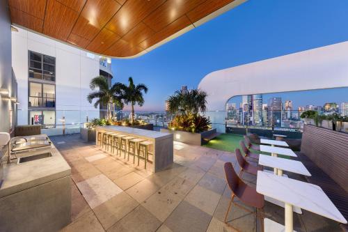 a rooftop patio with tables and chairs on a building at Art House Apartments by CLLIX in Brisbane