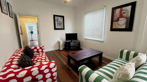 a living room with two couches and a table at Teke Cottage in Wooli