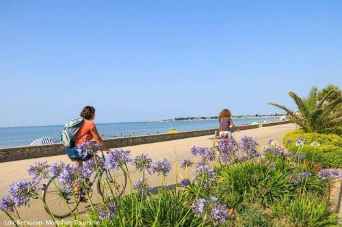 two people riding bikes on a beach with purple flowers at Ti nomad in Saint-Nolff