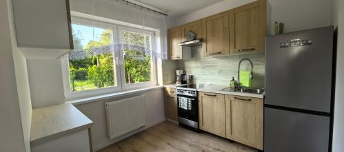 a kitchen with a refrigerator and a sink and a window at Dom Wakacyjny Koralowa 16, Osieki Zachodniopomorskie in Osieki