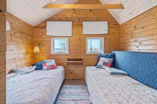 two beds in a room with wooden walls and windows at LF10999-Thyholm-Ringvejen-9 in Thyholm