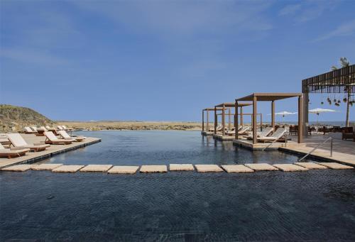a pool of water with lounge chairs on a beach at Alila Hinu Bay Salalah Mirbat in Salalah