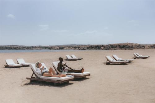 a group of people sitting in lounge chairs on a beach at Alila Hinu Bay Salalah Mirbat in Salalah