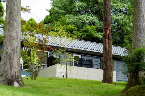 a building with a wall and trees in front of it at GRACE VILLA Aso Kurokawa in Minamioguni