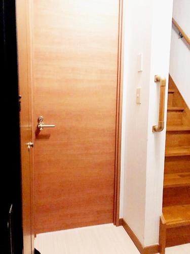 a wooden door leading into a hallway with stairs at Sweet House Sugamo 101 in Tokyo