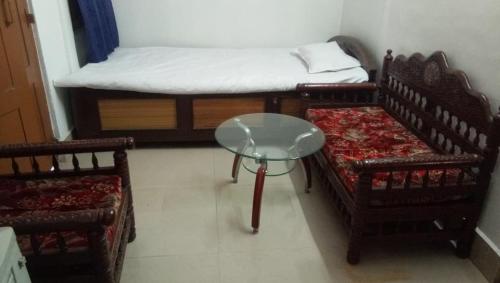 古瓦哈提Amaravati homestay的有两张床、一张桌子和几把椅子的房间