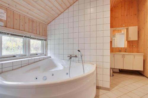 Una gran bañera blanca en un baño con ventana. en 1441-Aakirkeby-Strandparken-14, en Vester Sømarken