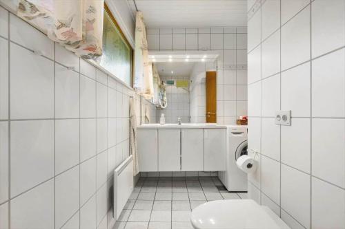 a white bathroom with a toilet and a sink at 5577-Gudhjem-Norrelokke-18 in Gudhjem