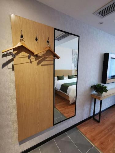 a room with a door with a mirror and a bed at GreenTree Inn Ganzhou Gan County Bus Station in Ganzhou