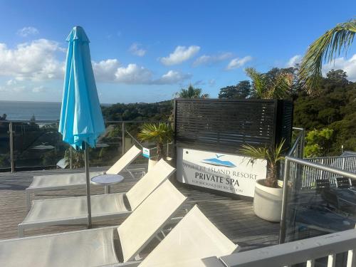 a patio with a blue umbrella and a sign at Deluxe Bedroom ldouble or twin bedl in shared Premium Villa at Waiheke Island Resort in Waiheke Island