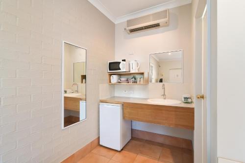 
a bathroom with a sink and a mirror at Catalina Motel Lake Macquarie in Toronto
