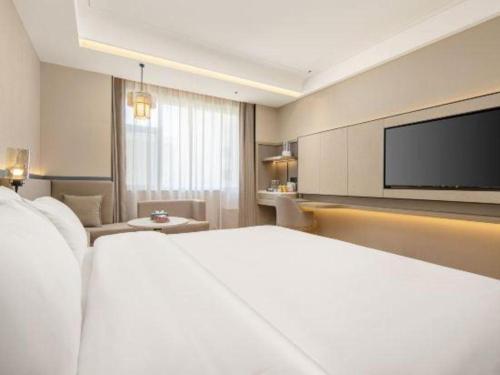 a hotel room with a bed and a flat screen tv at Tianrun International Hotel in Dunhuang