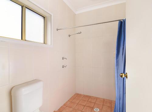 a bathroom with a shower curtain and a toilet at Catalina Motel Lake Macquarie in Toronto