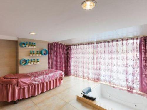 a bedroom with a tub and a bed and a bath tub at Harmony Resort Hotel Zhuhai in Zhuhai