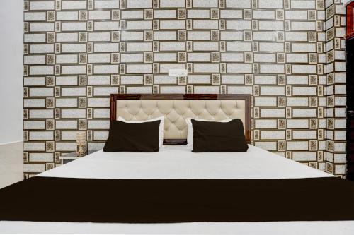 a bed with two pillows in front of a brick wall at SPOT ON The Soraon Residency in Phāphāmau