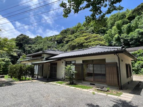 a small house with a mountain in the background at 甚兵衛邸 in Hirado