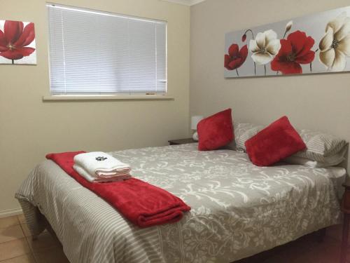 a bedroom with a bed with red pillows and a window at The Nosh & Nod - Avon Terrace in York