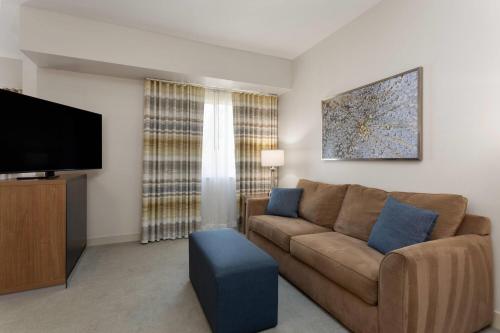 a living room with a couch and a flat screen tv at Hawthorn Extended Stay by Wyndham Naples in Naples