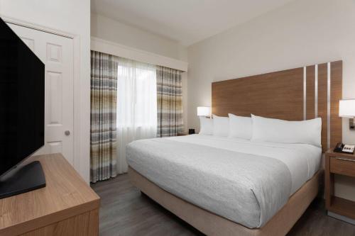 a bedroom with a large bed and a flat screen tv at Hawthorn Extended Stay by Wyndham Naples in Naples