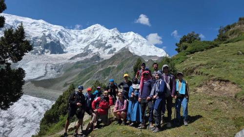 a group of people posing for a picture in front of a mountain at Rakaposhi Base Camp Site in Minapin