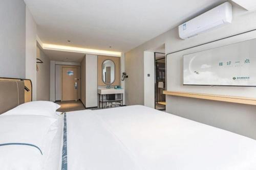 a bedroom with a large white bed and a flat screen tv at City Comfort Inn Wuhan Hankou Railway Station West Square in Wuhan