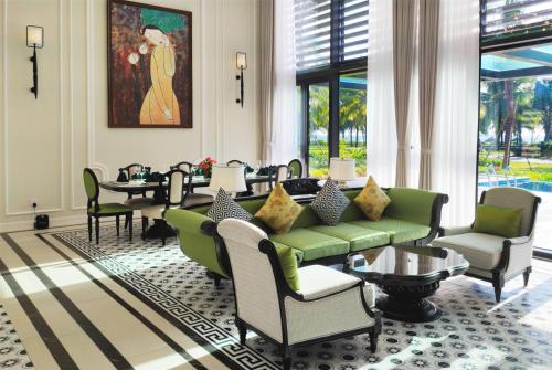 a living room with a green couch and chairs at Wyndham Grand Phu Quoc in Phu Quoc