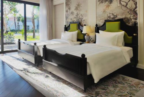 two beds in a bedroom with a large window at Wyndham Grand Phu Quoc in Phu Quoc
