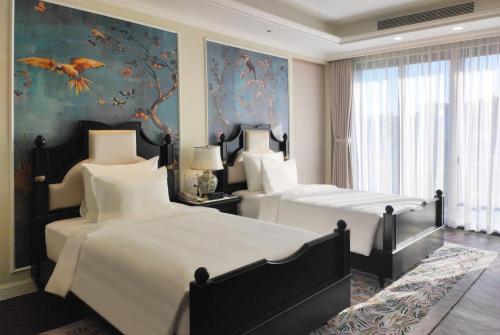 a bedroom with two beds and a painting of birds at Wyndham Grand Phu Quoc in Phu Quoc