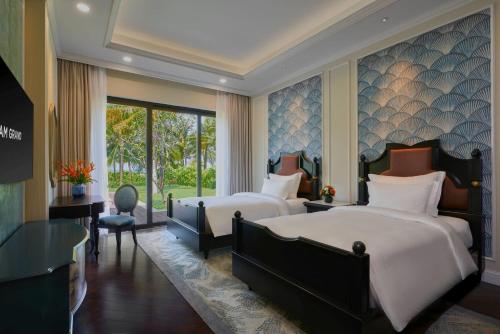 a hotel room with two beds and a desk at Wyndham Grand Phu Quoc in Phu Quoc