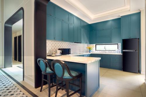 a kitchen with blue cabinets and two bar stools at Wyndham Grand Phu Quoc in Phu Quoc