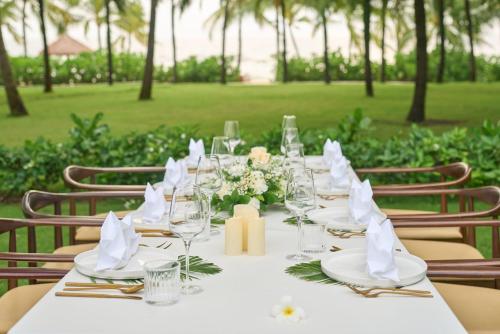 a long table with glasses and flowers on it at Wyndham Grand Phu Quoc in Phu Quoc