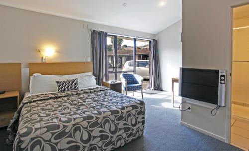 a hotel room with a bed and a flat screen tv at Walton Park Motor Lodge in Warkworth