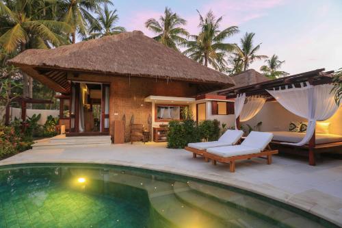 a villa with a swimming pool in front of a house at Pondok Santi Estate in Gili Trawangan