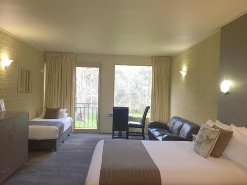 a hotel room with two beds and a couch at Madison Spa Motel - Adults Only in Moama