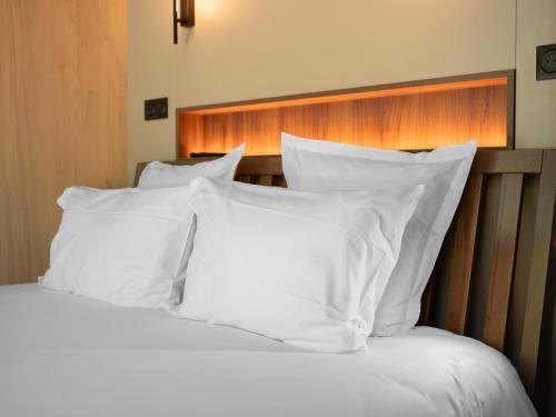 a white bed with white pillows and a wooden headboard at Logis Hôtel-Restaurant Domaine de Montecristo in Bourguignons