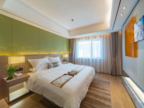 a bedroom with a large bed with a green wall at GreenTree Eastern Dali Railway Station Hotel in Dali
